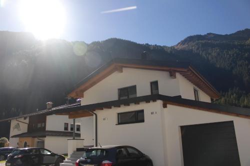 a building with cars parked in front of it at Apart Alpenjuwel in Sankt Leonhard im Pitztal