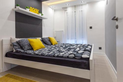a bed with yellow and grey pillows in a room at Park Apartment in Novi Sad