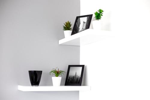 a white shelf with pictures and plants on it at Park Apartment in Novi Sad