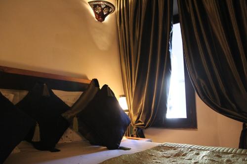 a bedroom with a bed with black pillows and a window at Riad Terra Bahia in Marrakech