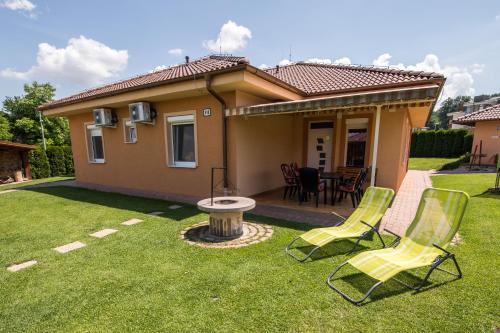 a yard with two lawn chairs and a house at Villa Gracia Podhájska in Podhájska