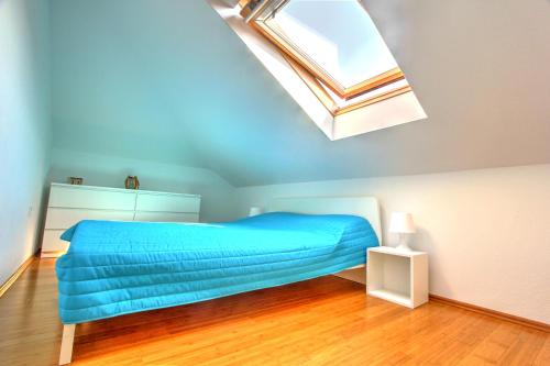 a bedroom with a blue bed and a skylight at Beachfront Apartment. 2xAC & BIKES in Postira