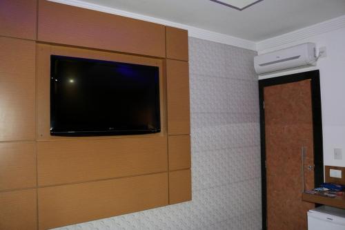 een kamer met een flatscreen-tv aan de muur bij Motel Fuego (Adults Only) in Betim