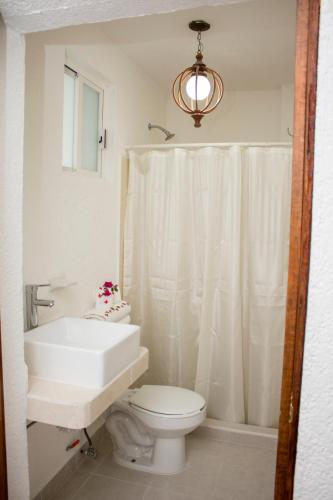 a white bathroom with a toilet and a sink at Villa Lupita in Zihuatanejo