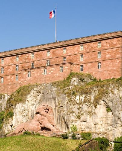 a building with a flag on top of a mountain at Novotel Belfort Centre Atria in Belfort