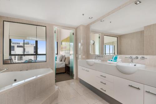 a bathroom with two sinks and a tub and mirror at Seamark on First in Mooloolaba