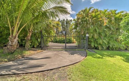 a driveway with a gate in a park with palm trees at Hale paradise in Keaau