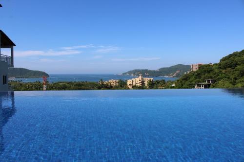 a swimming pool with a view of the ocean at Sunset House Zihuatanejo in Zihuatanejo