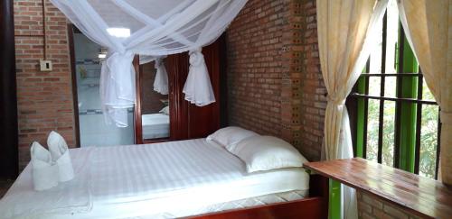 a bedroom with a bed in a brick wall at Green Hope Lodge in Cat Tien