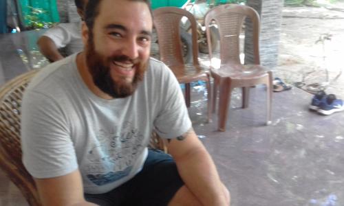 a man sitting in a chair smiling at the camera at Marari Bethsaida Homestay in Shertallai