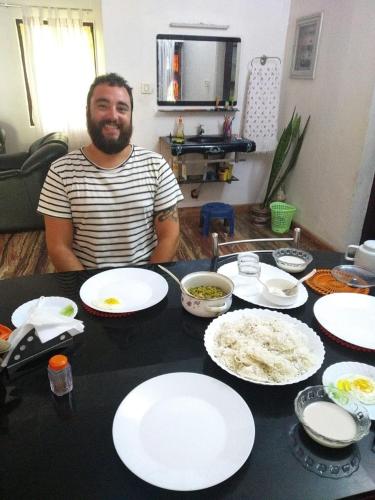 a man sitting at a table with plates of food at Marari Bethsaida Homestay in Shertallai