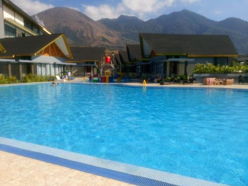a large blue swimming pool with mountains in the background at Cahaya Villa Garut in Garut