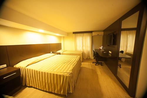 a hotel room with two beds and a desk at Hotel Plaza Apolo in Sao Paulo