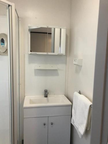 a white bathroom with a sink and a mirror at Peppermint Grove Beach Holiday Park in Capel