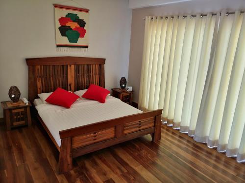 a bedroom with a bed with two red pillows at Corto del Mar Hotel in Coron