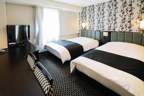 a hotel room with two beds and a television at APA Hotel Sapporo Susukino Ekimae in Sapporo
