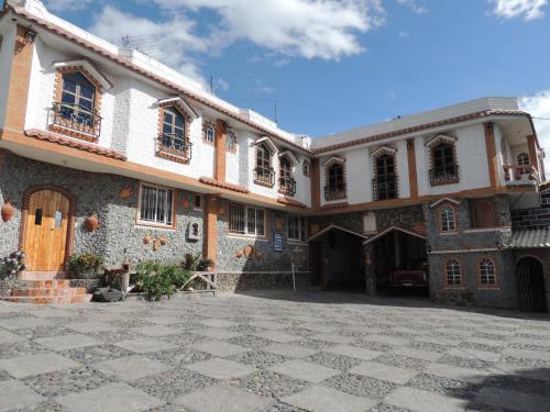 ein großes Gebäude mit einem steinernen Innenhof mit einem Gebäude in der Unterkunft Hostal Ñuca Huasi in Tambillo