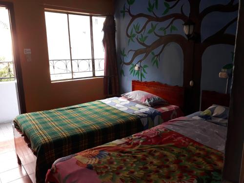 two beds in a room with a tree mural on the wall at Transilvania in Baños
