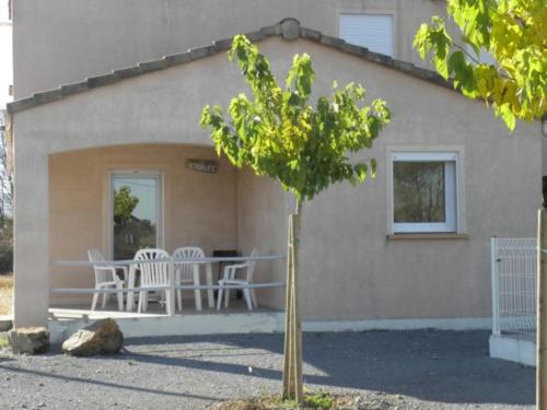 a small tree in front of a house with a table and chairs at les cigales in Lablachère