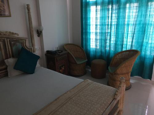 a bedroom with a bed and two wicker chairs at Little Ganesha Inn in Jaipur