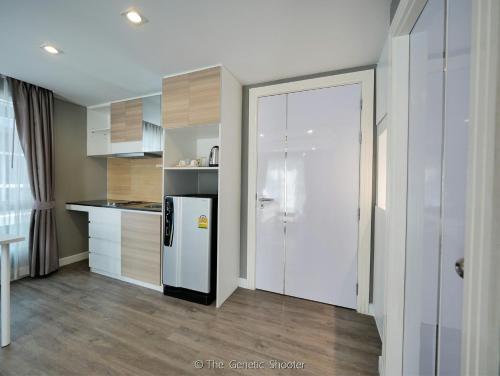 a kitchen with a white refrigerator and wooden cabinets at Wisdom Hotel & Residence in Rayong