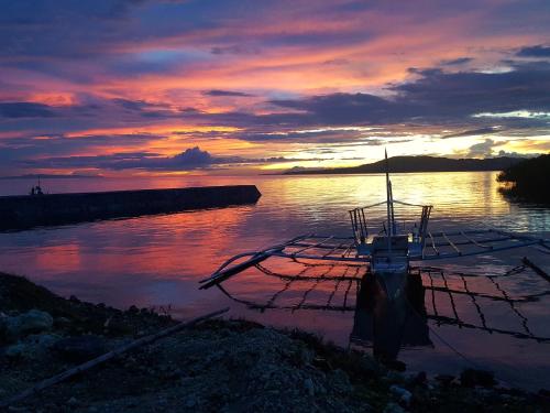 a boat sitting in the water at sunset at MJ Room Rental in Panglao