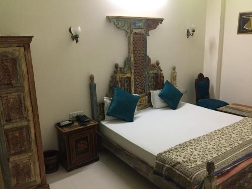 a bedroom with a bed with blue pillows at Little Ganesha Inn in Jaipur