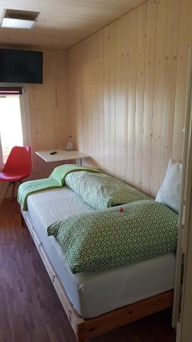 a bed in a room with a wooden wall at b&b krättli in Eggiwil