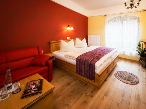 a hotel room with a bed and a red couch at Pullman City Westernstadt in Eging