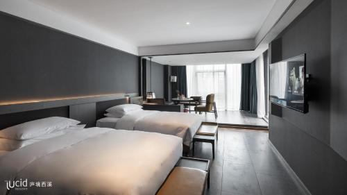 um quarto de hotel com duas camas e uma mesa em The Lucid Hangzhou XiXi Wetland Hotel em Hangzhou