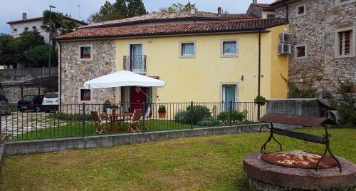 a house with a table and an umbrella in a yard at Torretta sul Colle in Colle Umberto