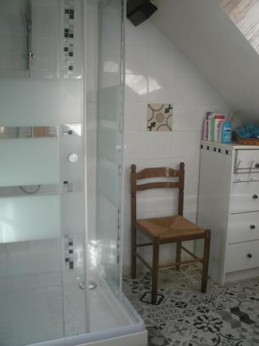 La salle de bains est pourvue d'une douche et d'une chaise en bois. dans l'établissement Chambres d'hotes du Moulin, à Saint-Julien-sur-Cher