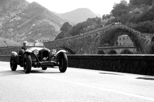 a black and white photo of a car driving on a bridge at Lucca Franco's Villa in Diecimo