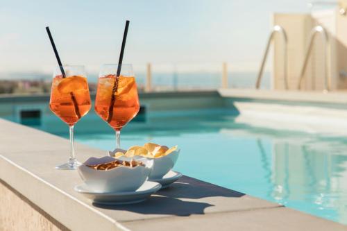 due bicchieri di vino e una ciotola di cibo accanto alla piscina di Savoy Hotel a Marina di Pietrasanta