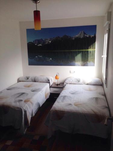 two beds in a room with a picture on the wall at El Lagar in Aller