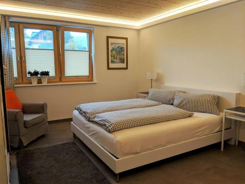 a bedroom with a bed and a chair and a window at dasGams in Gosau