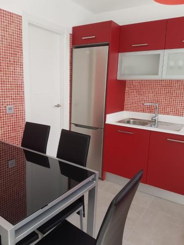 a kitchen with red cabinets and a sink and chairs at Vivienda Aries in Puerto del Carmen