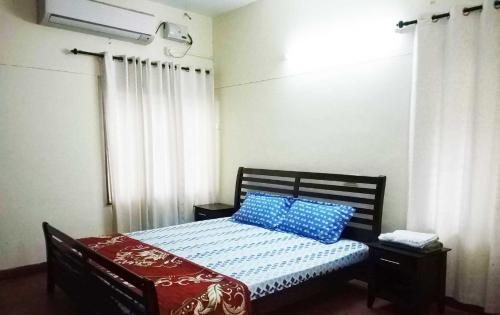 a bedroom with a bed with blue pillows on it at Tagore Homestay Villa Trivandrum in Trivandrum