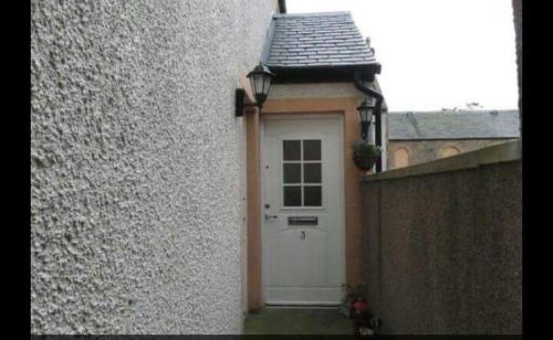 a white door on the side of a building at 3 coach house balnagown in Tain