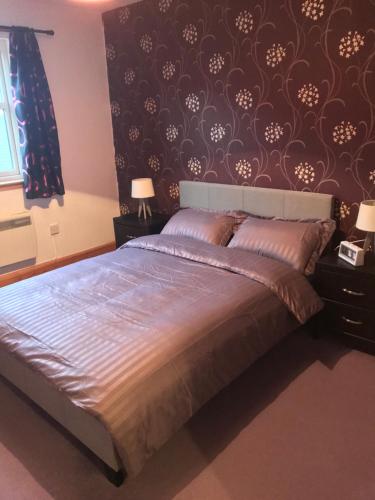 a bedroom with a large bed with a black wall at 3 coach house balnagown in Tain