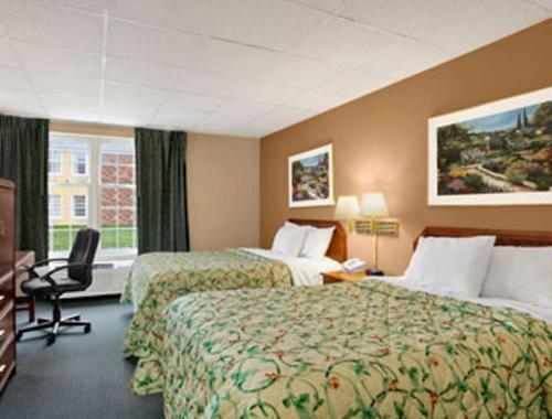 マディソンビルにあるDays Inn by Wyndham Madisonvilleのベッド2台とデスクが備わるホテルルームです。