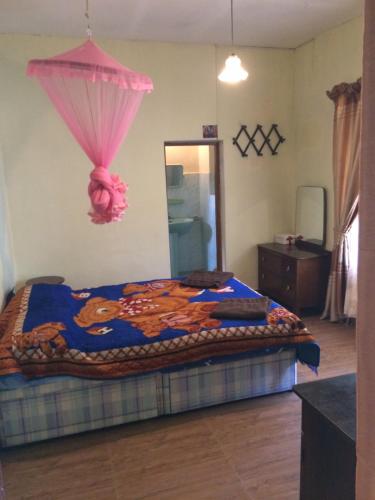 um quarto com uma cama king-size e um guarda-chuva rosa em Jayawimana em Kandy