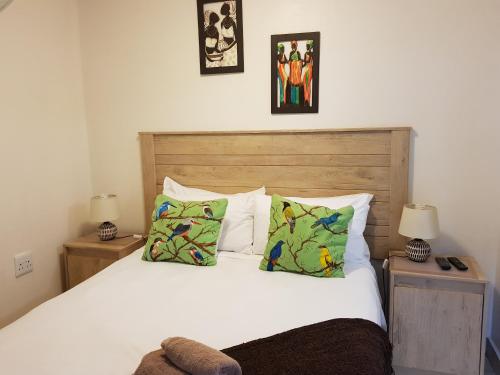 1 dormitorio con 1 cama blanca grande con almohadas en African Dwarf Kingfisher Guesthouse, en Eshowe