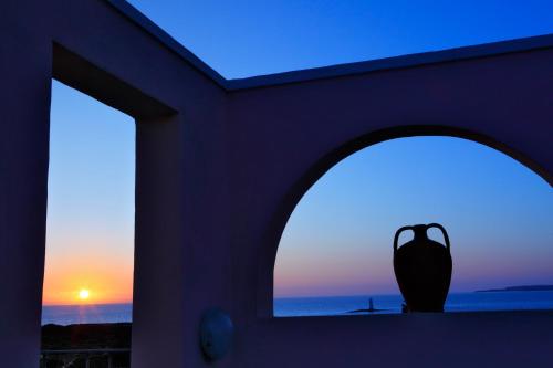 a vase sitting in a window with a sunset at Hotel Luci Del Faro in Calasetta
