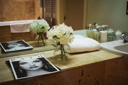 un mostrador de baño con flores y una foto de una mujer en The Windsor Town House, en Bath