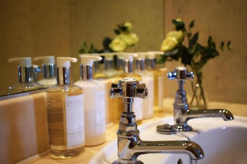 a bathroom sink with aaucet and some bottles of soap at The Windsor Town House in Bath