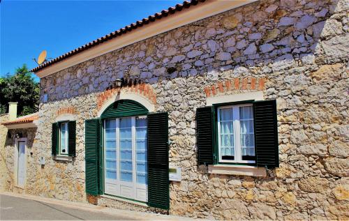 a stone building with green window shutters on it at Casa Rustica do Lagar in Lamas
