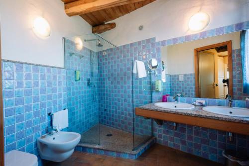 bagno piastrellato blu con 2 lavandini e servizi igienici di Hotel Luci Del Faro a Calasetta