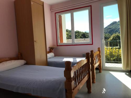 sypialnia z 2 łóżkami i oknem z widokiem w obiekcie Les chambres et studios Camping Parc de Paletès w mieście Saint-Girons