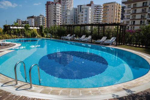 a large blue swimming pool with chairs and buildings at Upart Home in Mersin